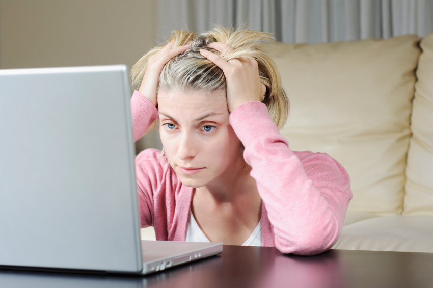 A frustrated looking woman glares at her laptop.