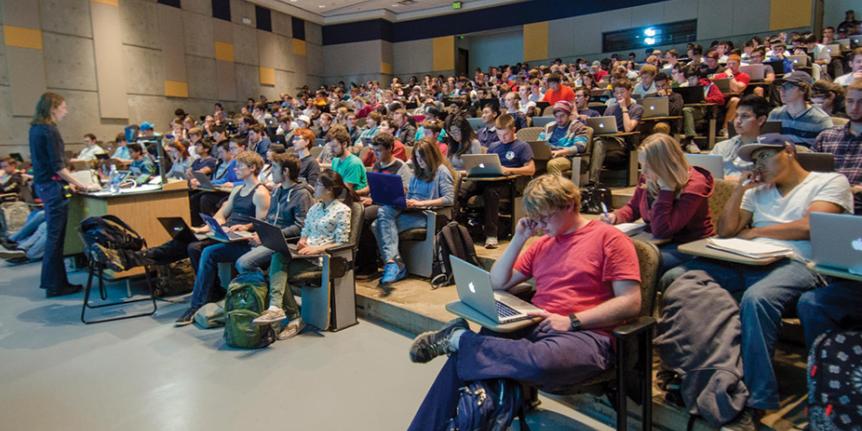 Students use their laptops during a lecture in a large classoom.