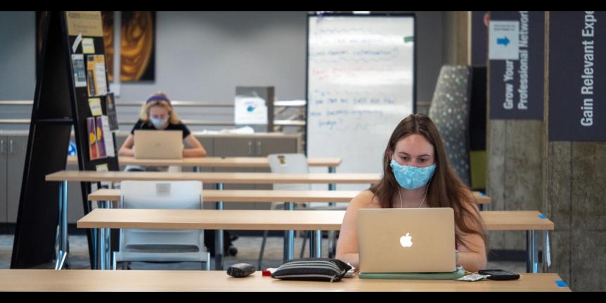 Decorative photo: masked students using laptops.