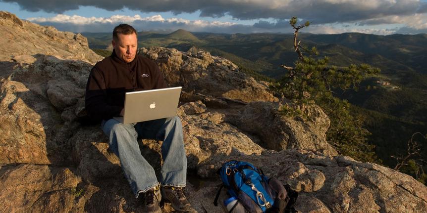 Someone using their laptop on a mountain.