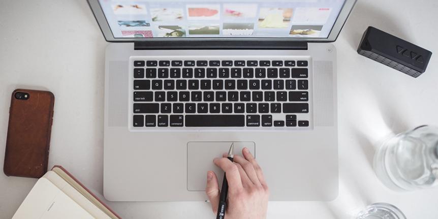 Decorative photo: laptop, phone, and notebook are pictured.