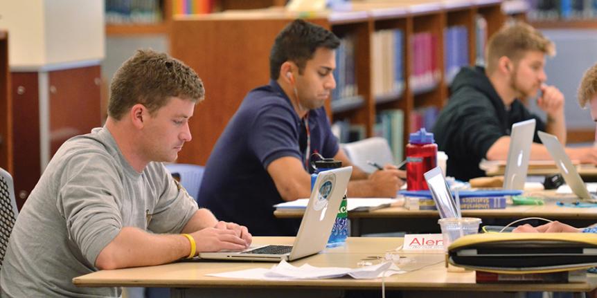 Students using laptops in library.