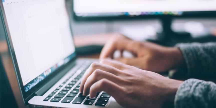 Hands are visible typing on a laptop computer