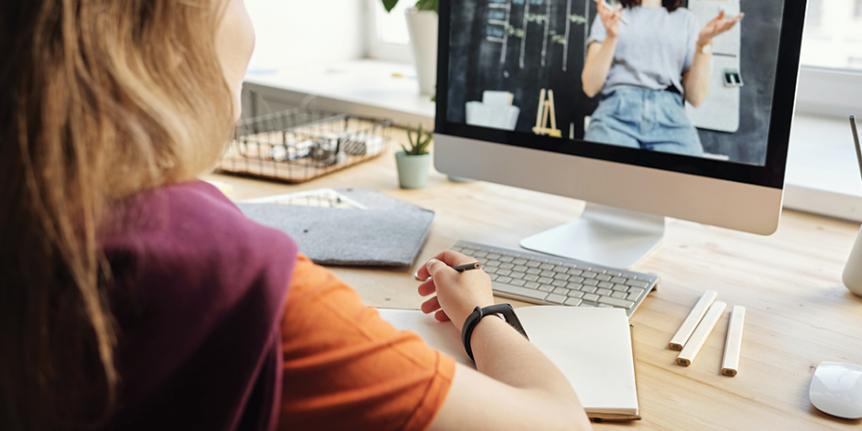 A young woman watches an online lecture on her computer.